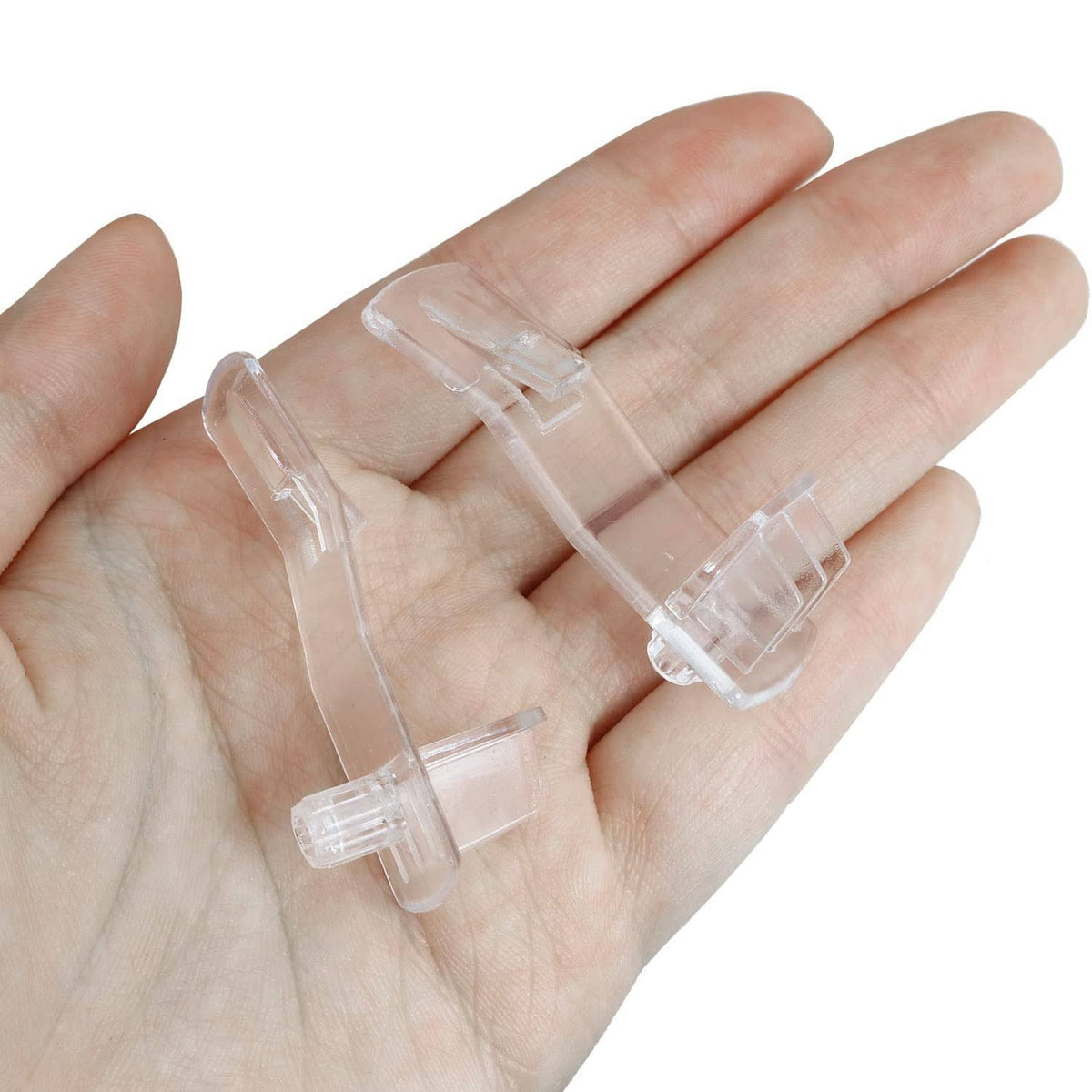 Clear plastic shelf support pegs held in hand, showing small locking pins