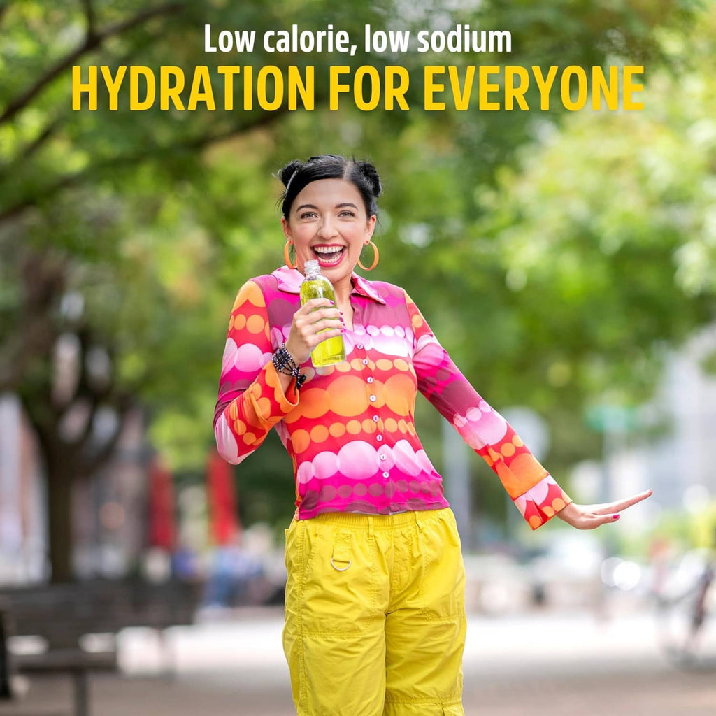 Lemonade electrolyte stick held by smiling person in colorful top and yellow pants