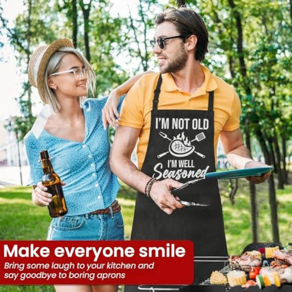 Black grilling apron set with 'I'm well seasoned' text, two people holding a tray