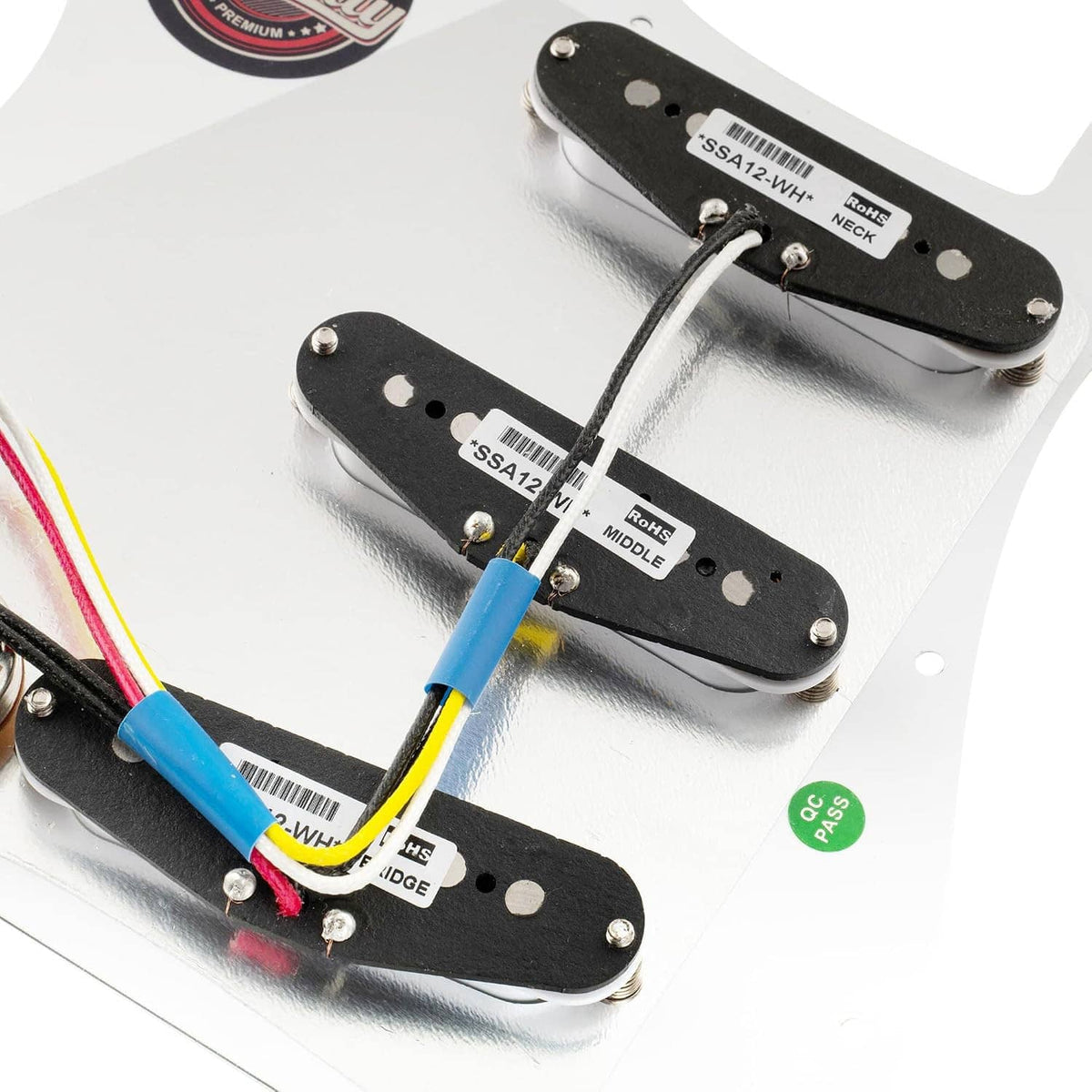 Close-up of black pickups on white pre-wired pickguard with labeled terminals and wires