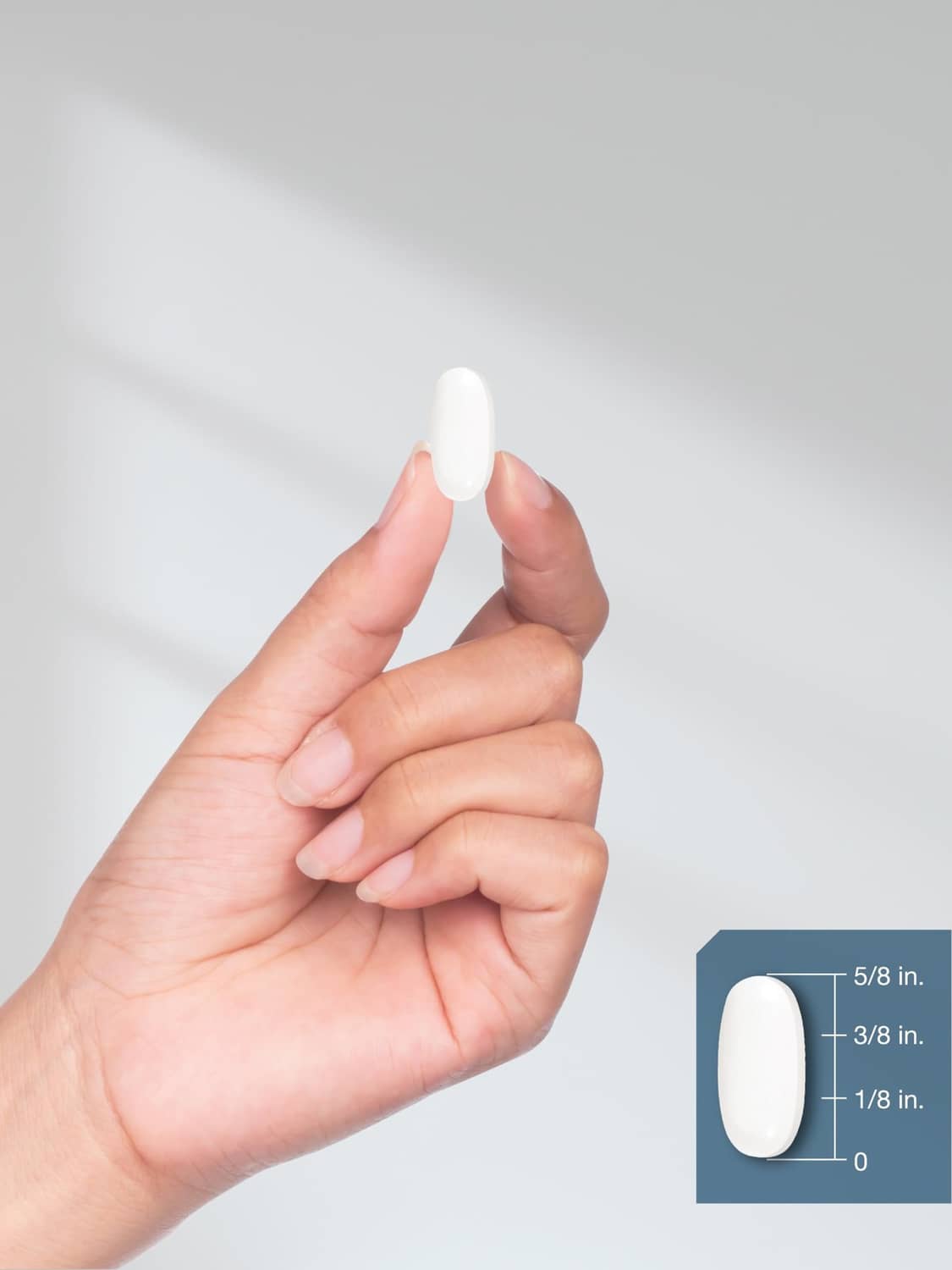 White magnesium oxide coated caplet held between fingers with size guide inset