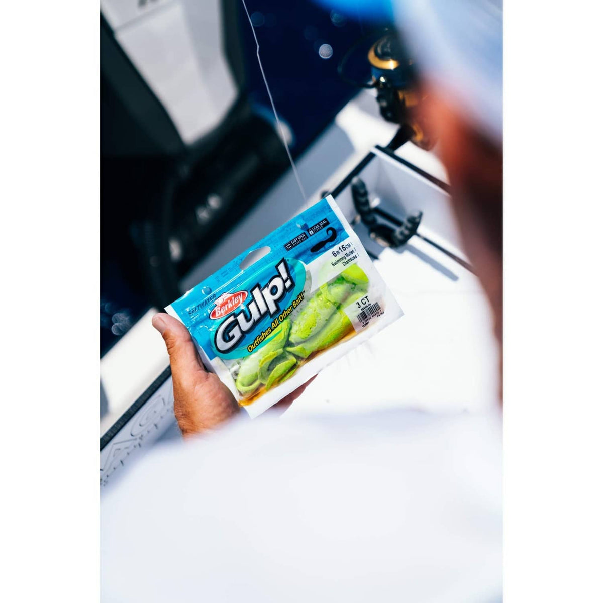 Hand holding Berkley Gulp bait pouch, blue-and-green label