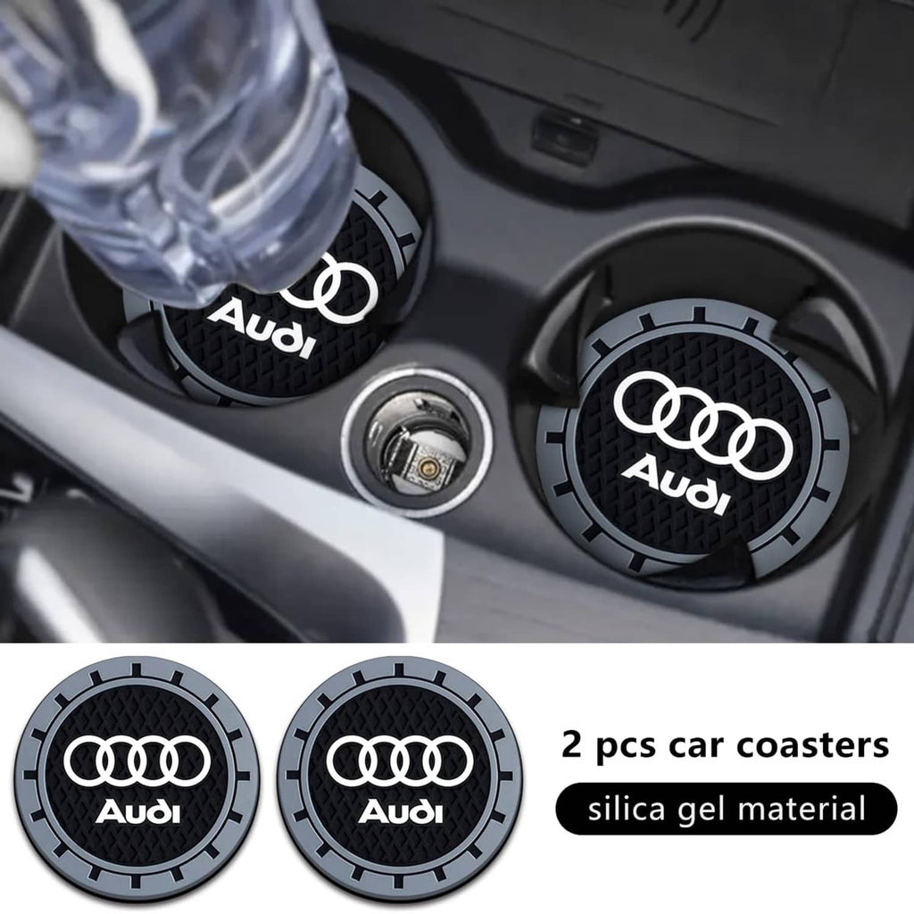 Two Audi logo car cup holder coasters, black textured inserts with grey outer ring