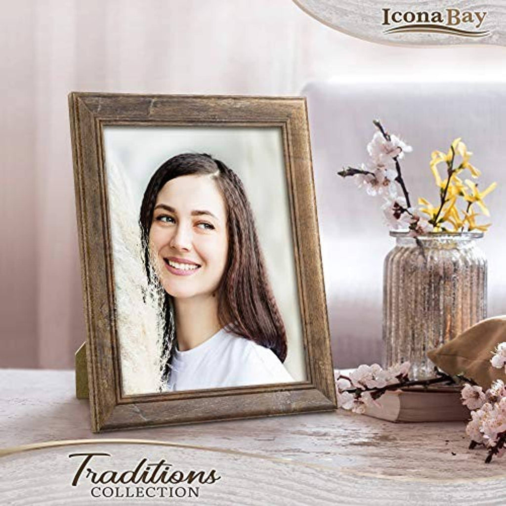 Chestnut brown rustic wood picture frame standing on a tabletop with flowers nearby