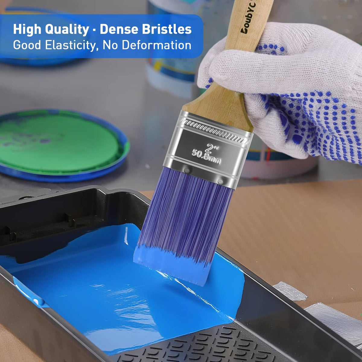Flat paint brush dipping into blue paint, purple bristles on wood handle