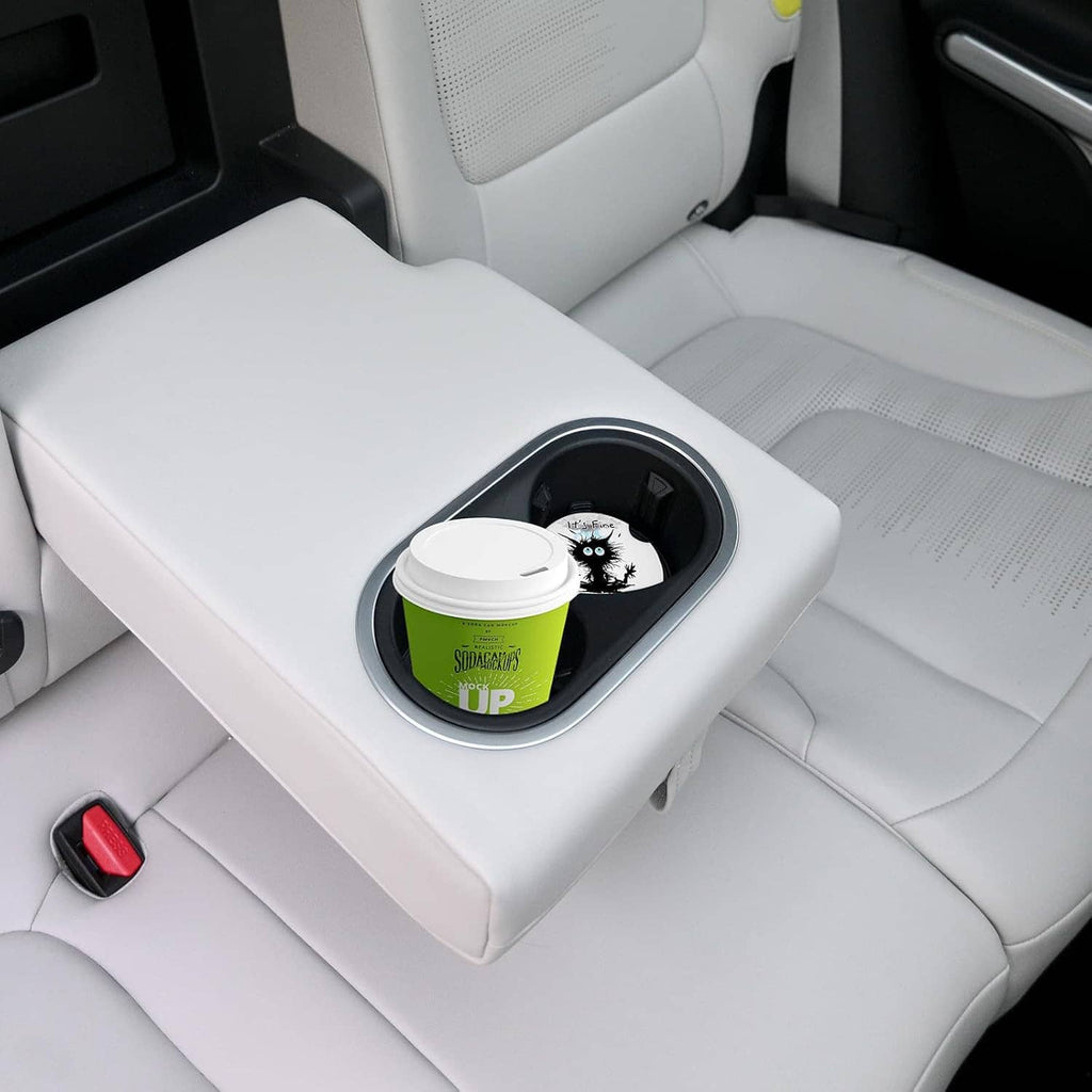 Round ceramic car coasters in cupholder holding a white lid and green cup