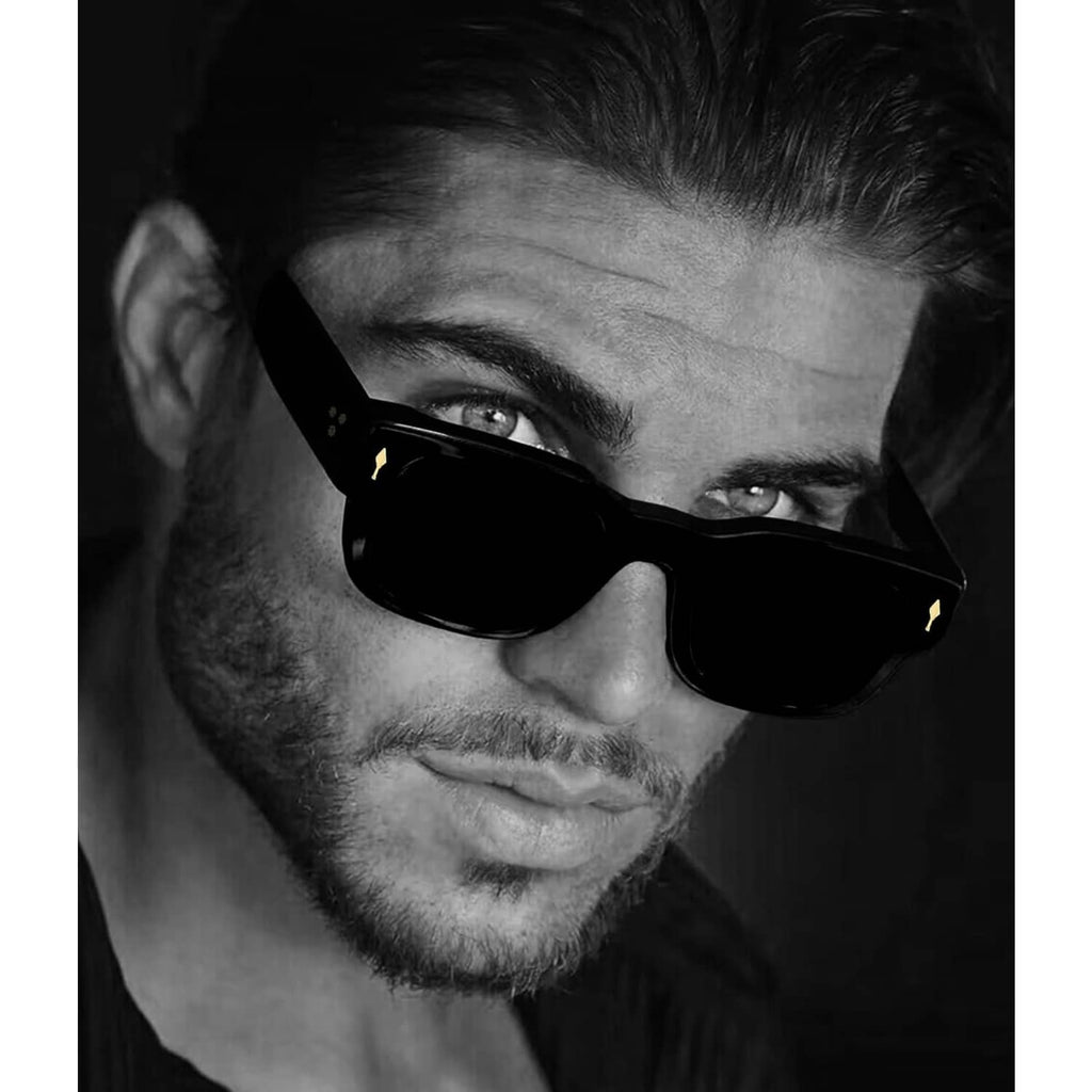 Black thick square sunglasses worn close-up, showing dark lenses and bold frame