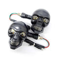 Pair of black skull-shaped LED motorcycle turn signal lights with wiring harness