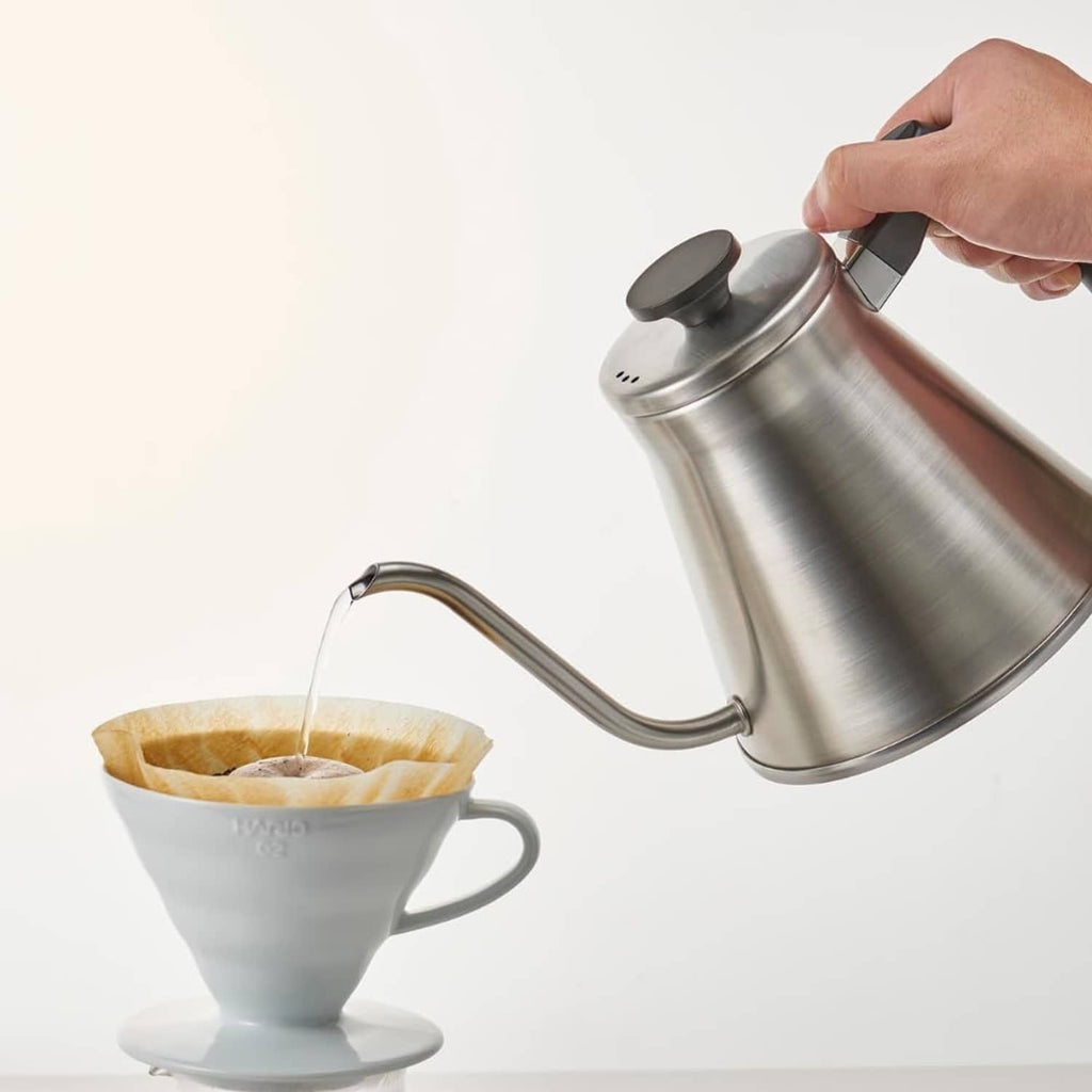 Paper coffee filter on dripper while hot water pours in