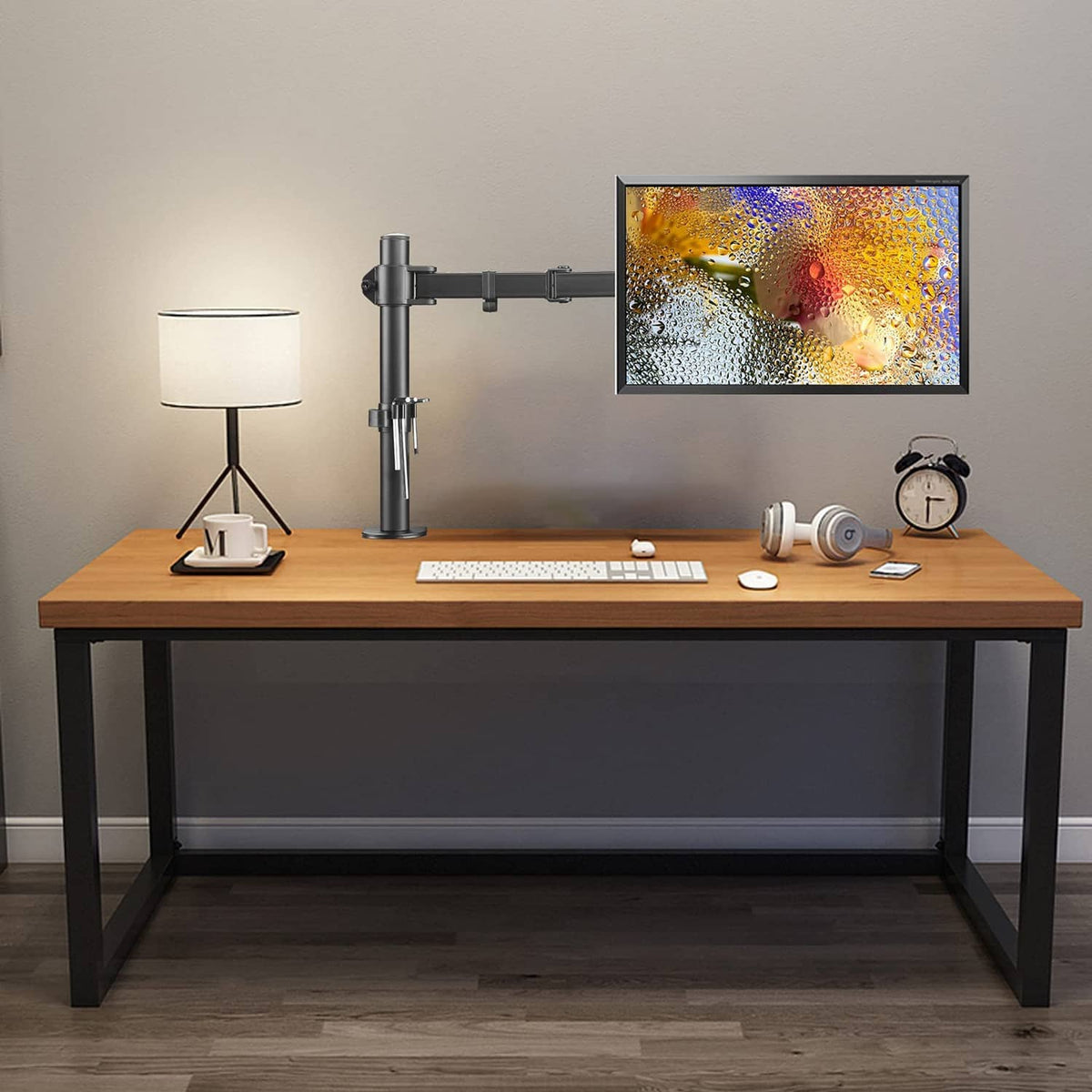 Single monitor arm mounted on a desk supporting a flat-screen display, black