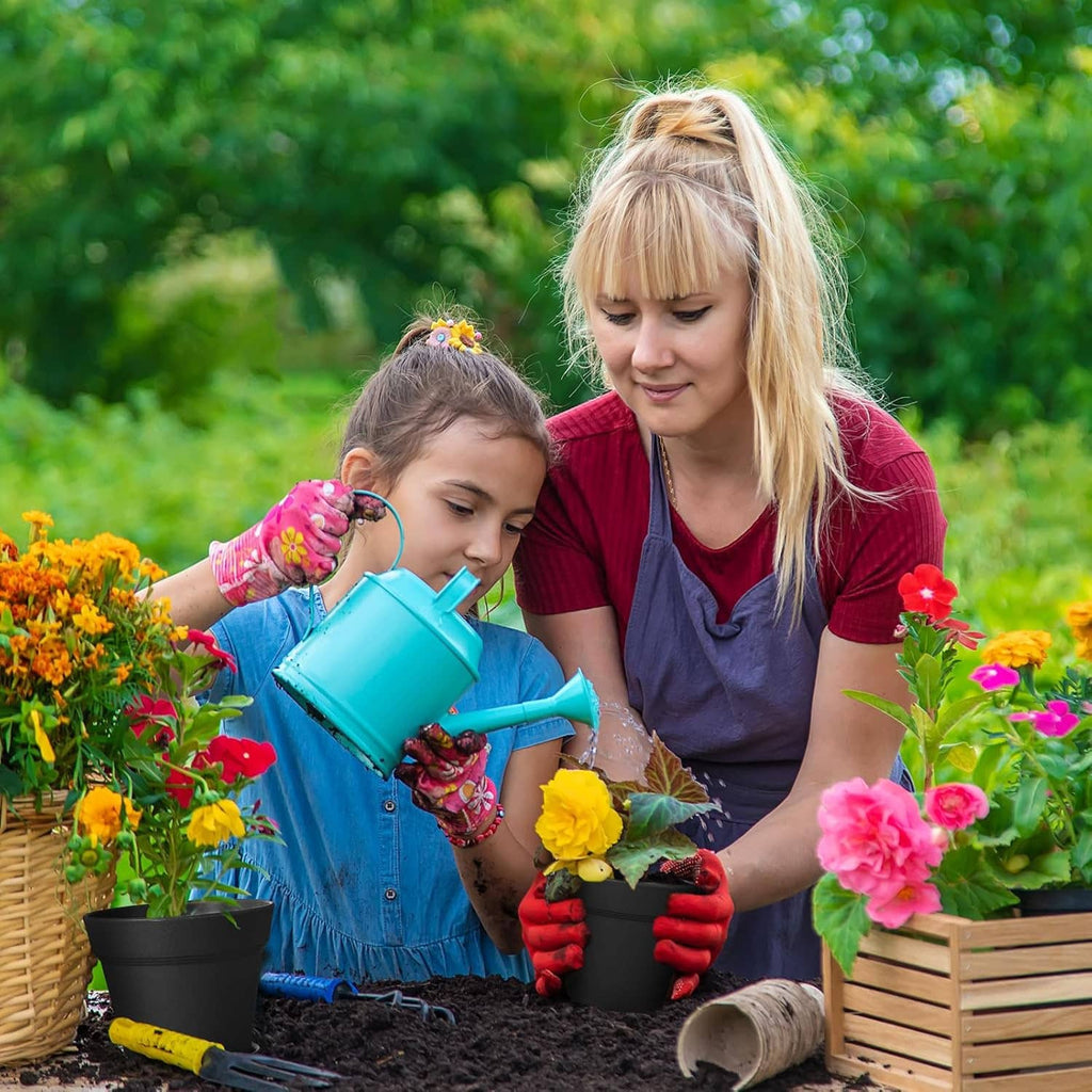 4-inch black plant pots filled with soil and flowers, held by a child and adult.