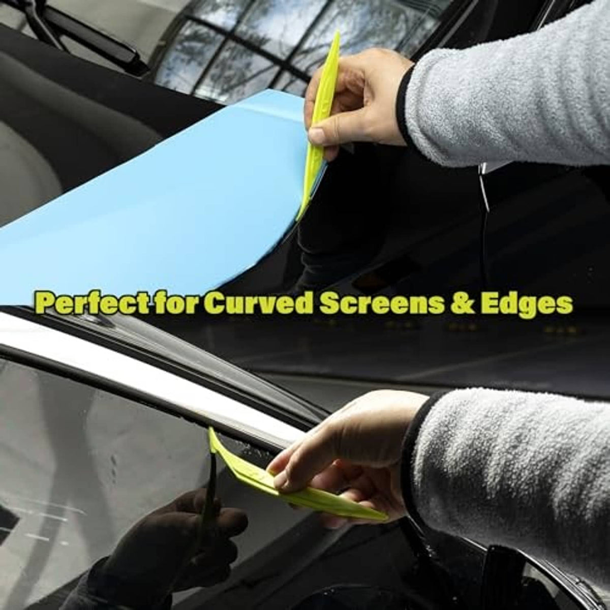 Hand smooths vinyl wrap onto a car edge using a lime double-edge tucking tool