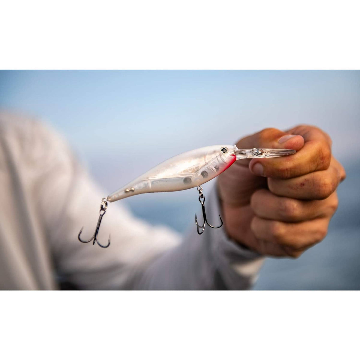 Shad-style white crankbait with red head and three treble hooks in hand