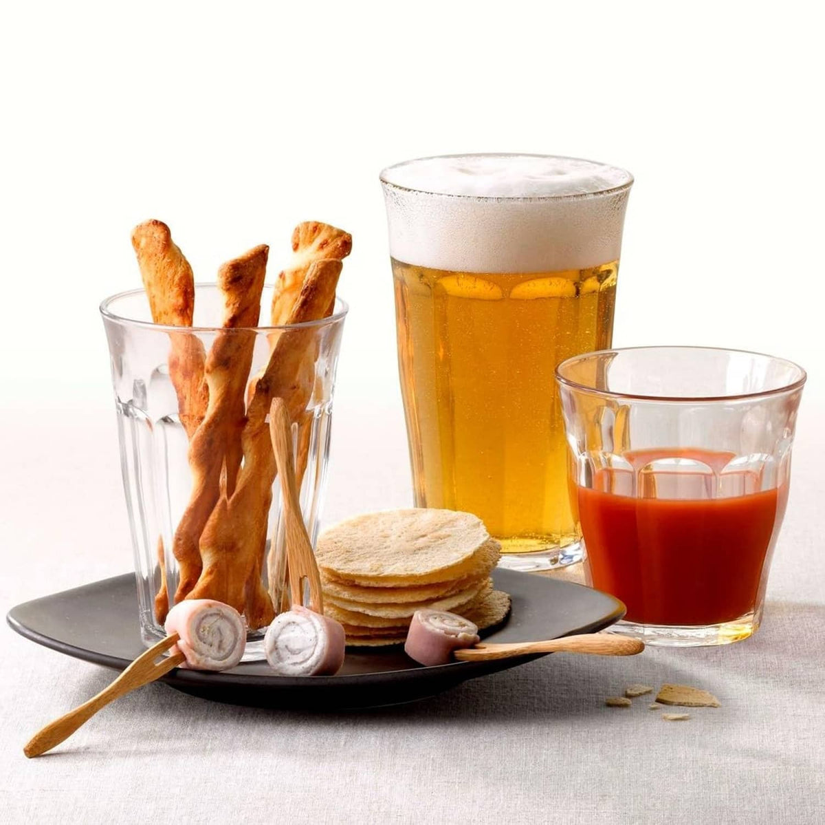 Set of clear glass tumblers with amber beverage and crackers