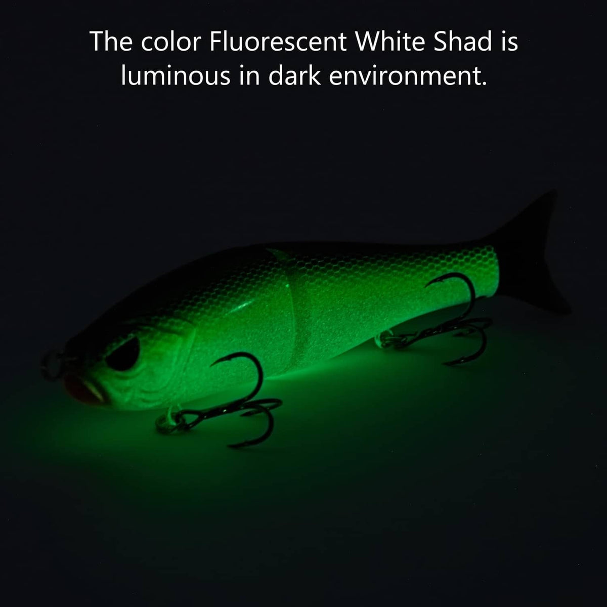 Fluorescent green glide bait with treble hooks, glowing in dark conditions