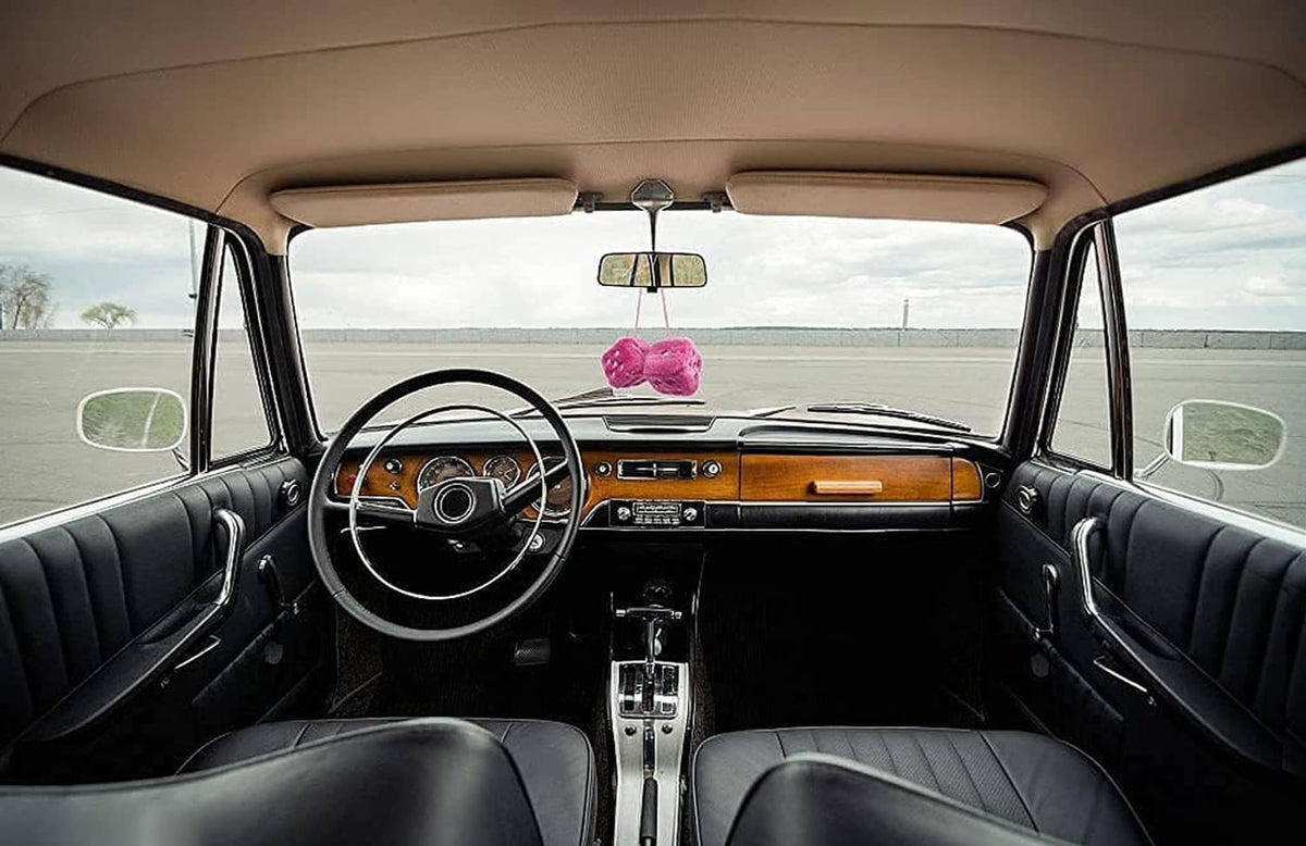Pink plush dice hanging from the car ceiling near the rear window
