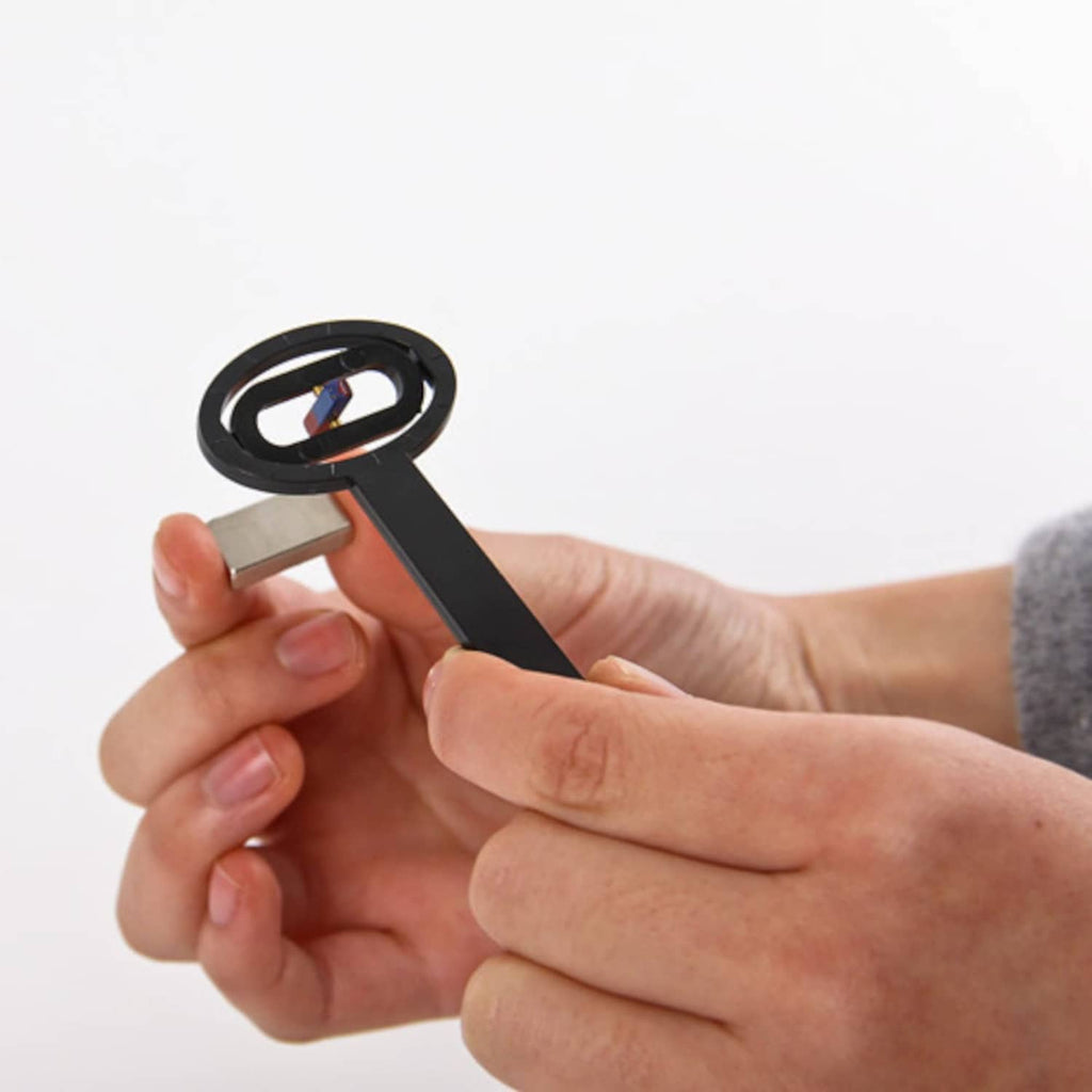 Magnetic pole detector tool held in hand with black circular ring