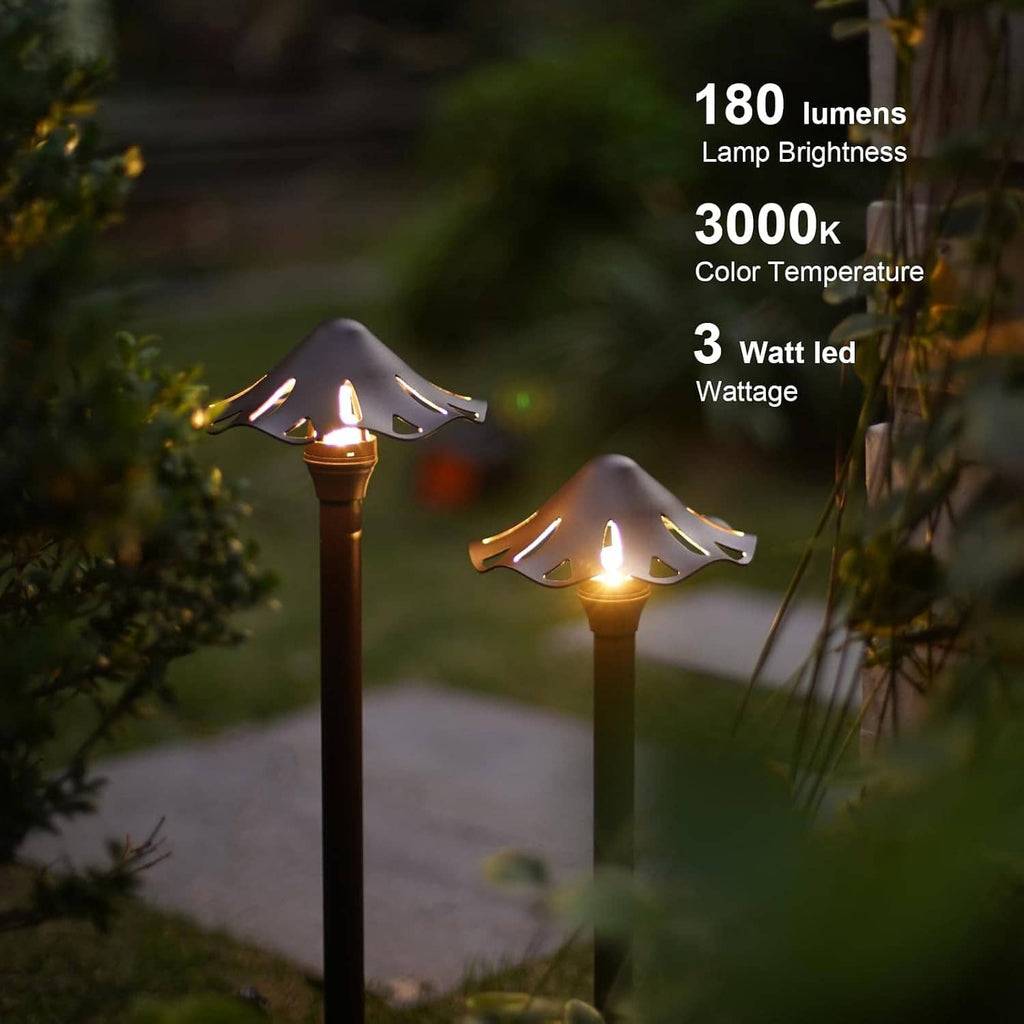Two lit low-voltage LED pathway lights in a garden, featuring decorative perforated caps
