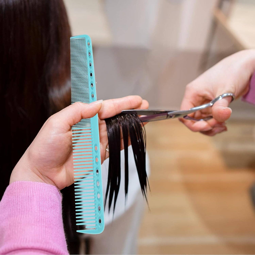Teal cutting comb held against dark hair while trimming with scissors