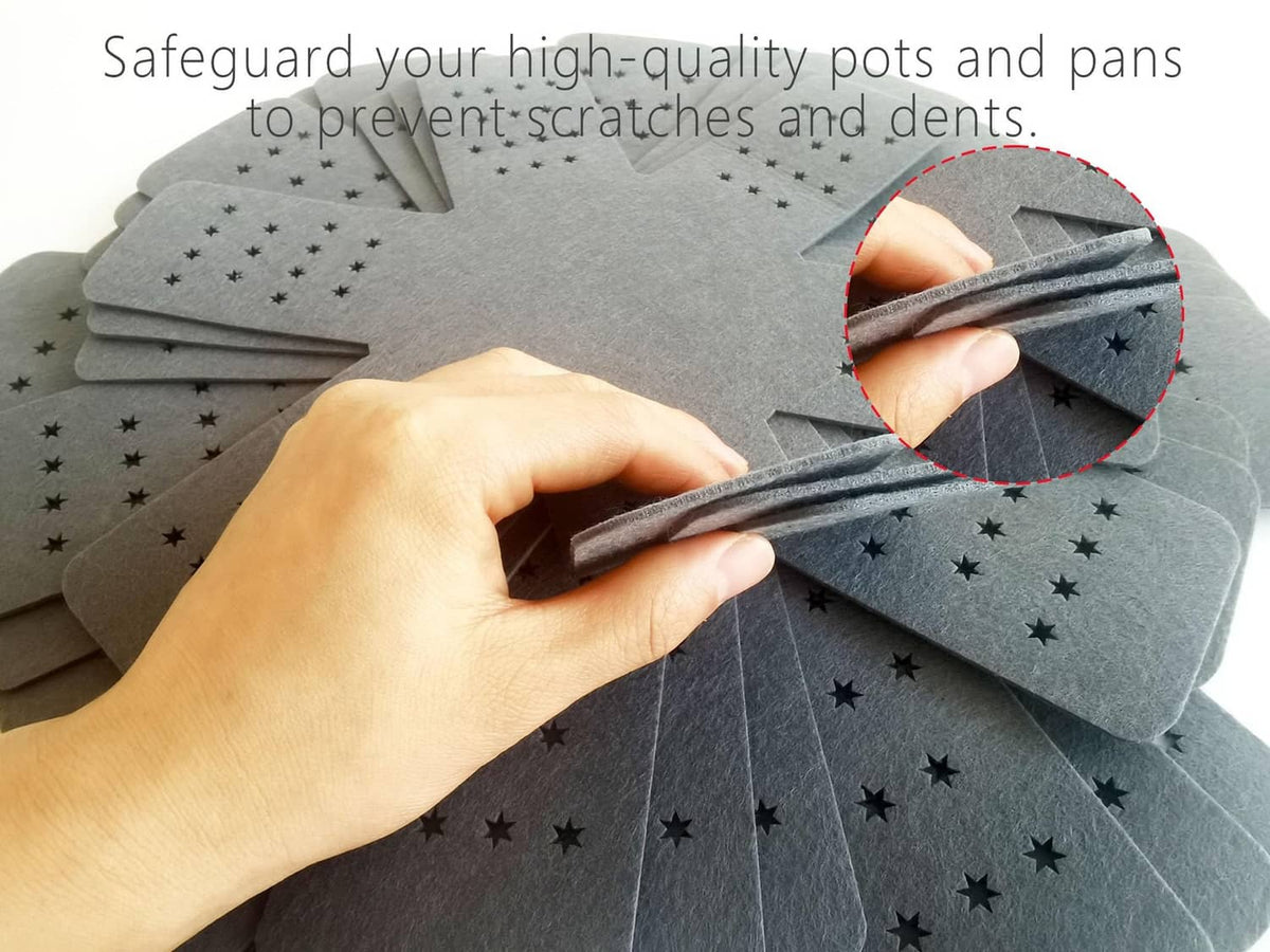 Gray pot and pan protectors with star-dot holes beneath a hand placing cookware.
