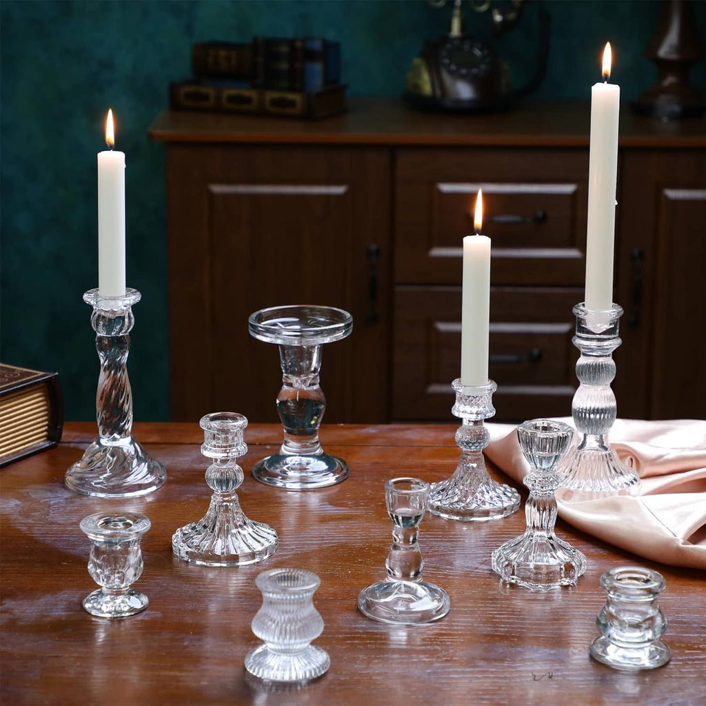 Clear glass taper candle holders with ribbed stems and round bases on wooden table