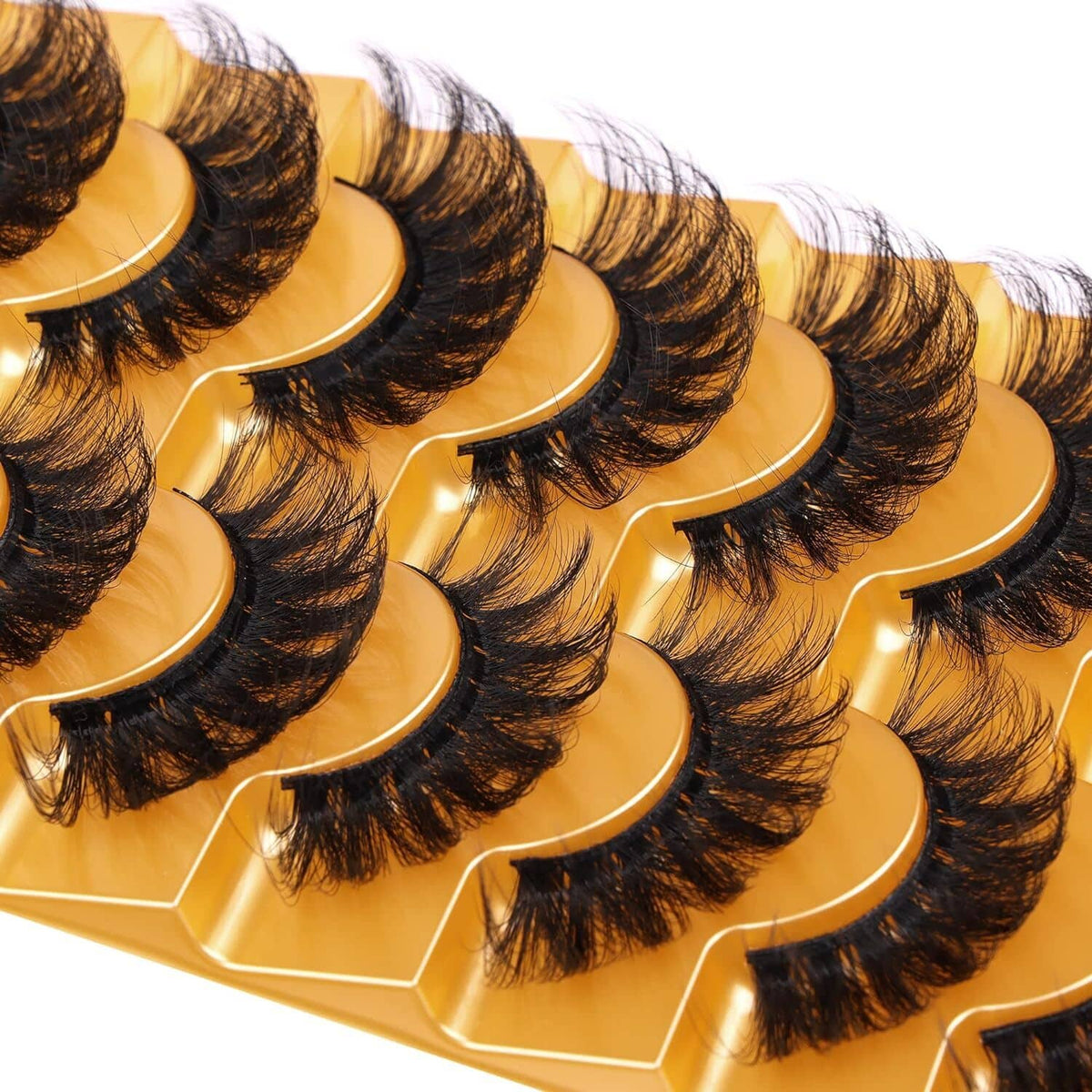 Close-up of fluffy curled false eyelash strips with golden bands in an organizer tray