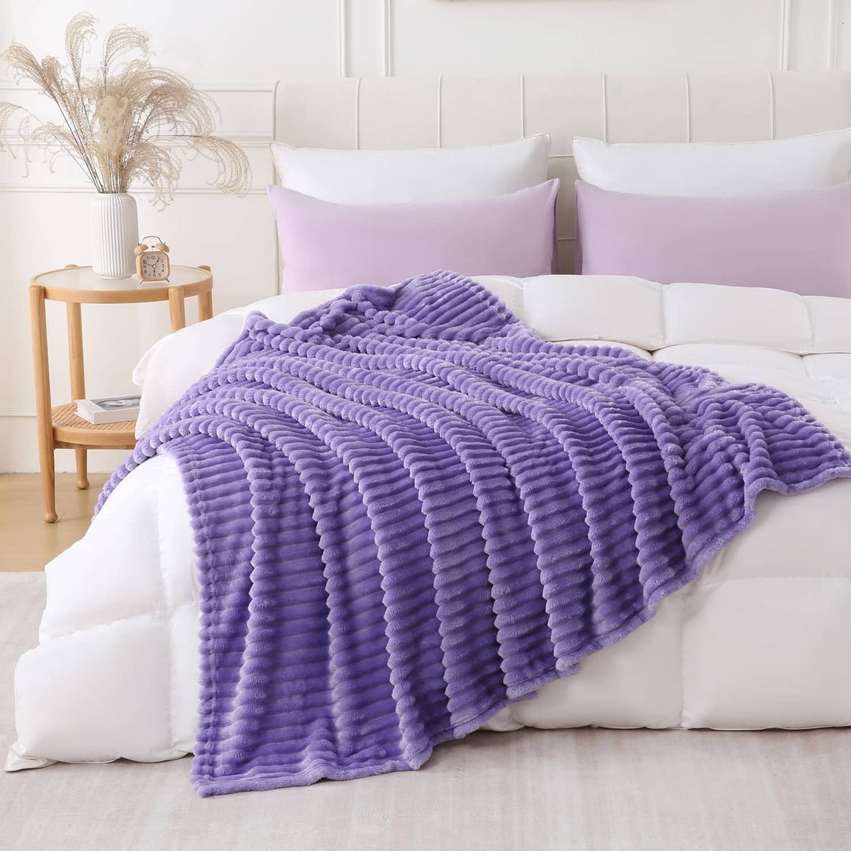 Lavender plush throw blanket with chunky striped ridges, spread across bed