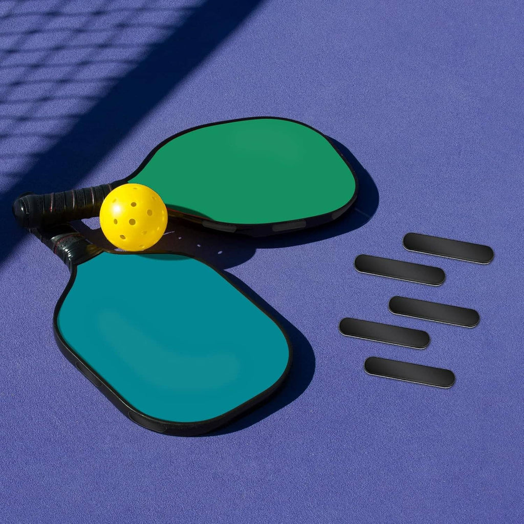 Pickleball paddles with black lead tape strips and separate tape pieces for placement.