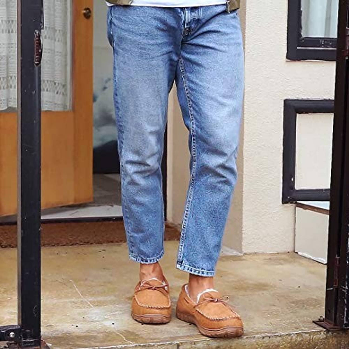 Men’s brown moccasin slippers worn with blue jeans and lace-up bow design