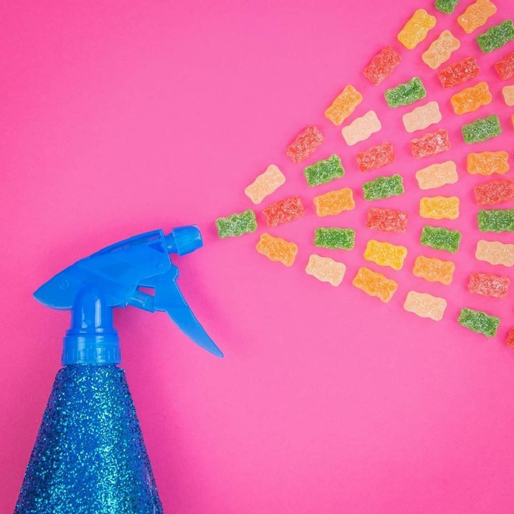 Sour gummi bears scattered around a blue spray bottle