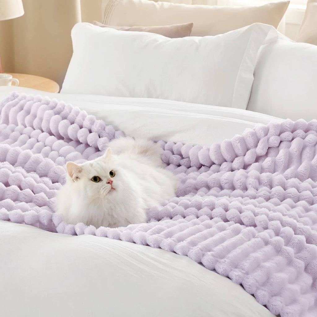 Lavender fog plush blanket with cat resting on the quilted surface