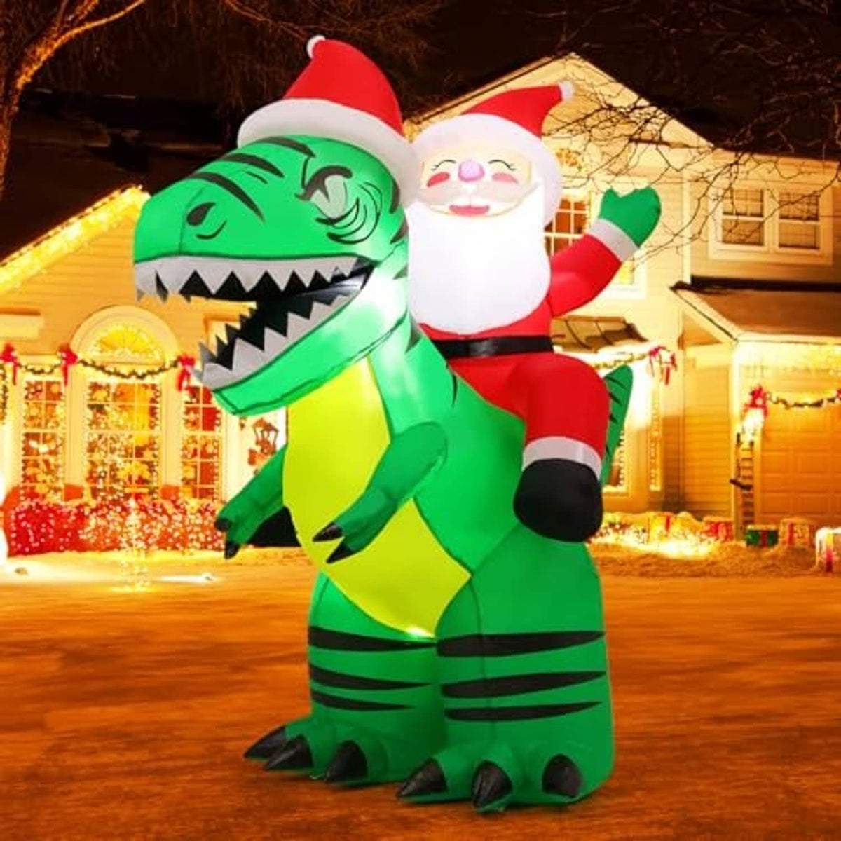 Inflatable Santa riding green crocodile standing in yard at night with warm lights