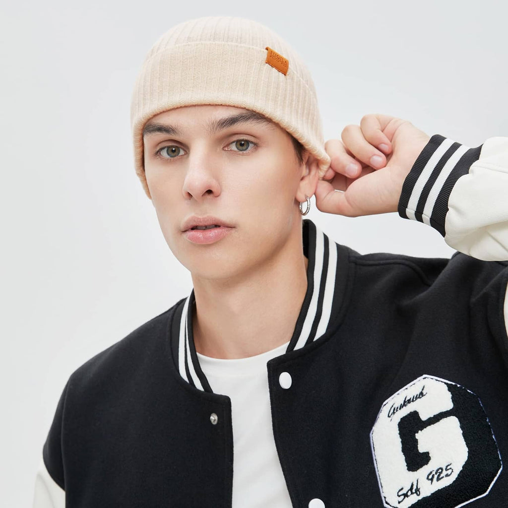 Beige knit beanie on model with folded cuff and small leather logo patch