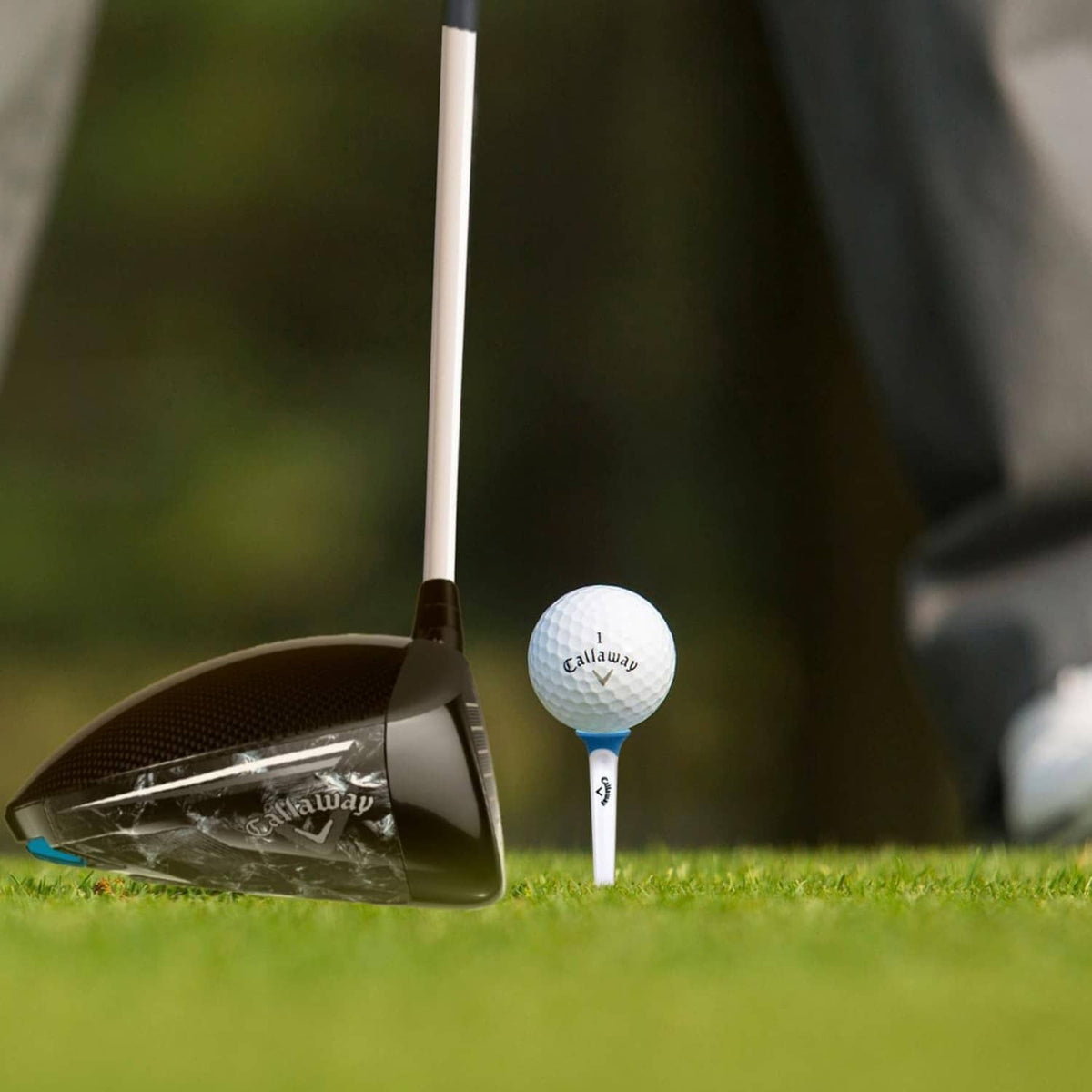 Callaway golf tee holding a white ball beside a club on the course