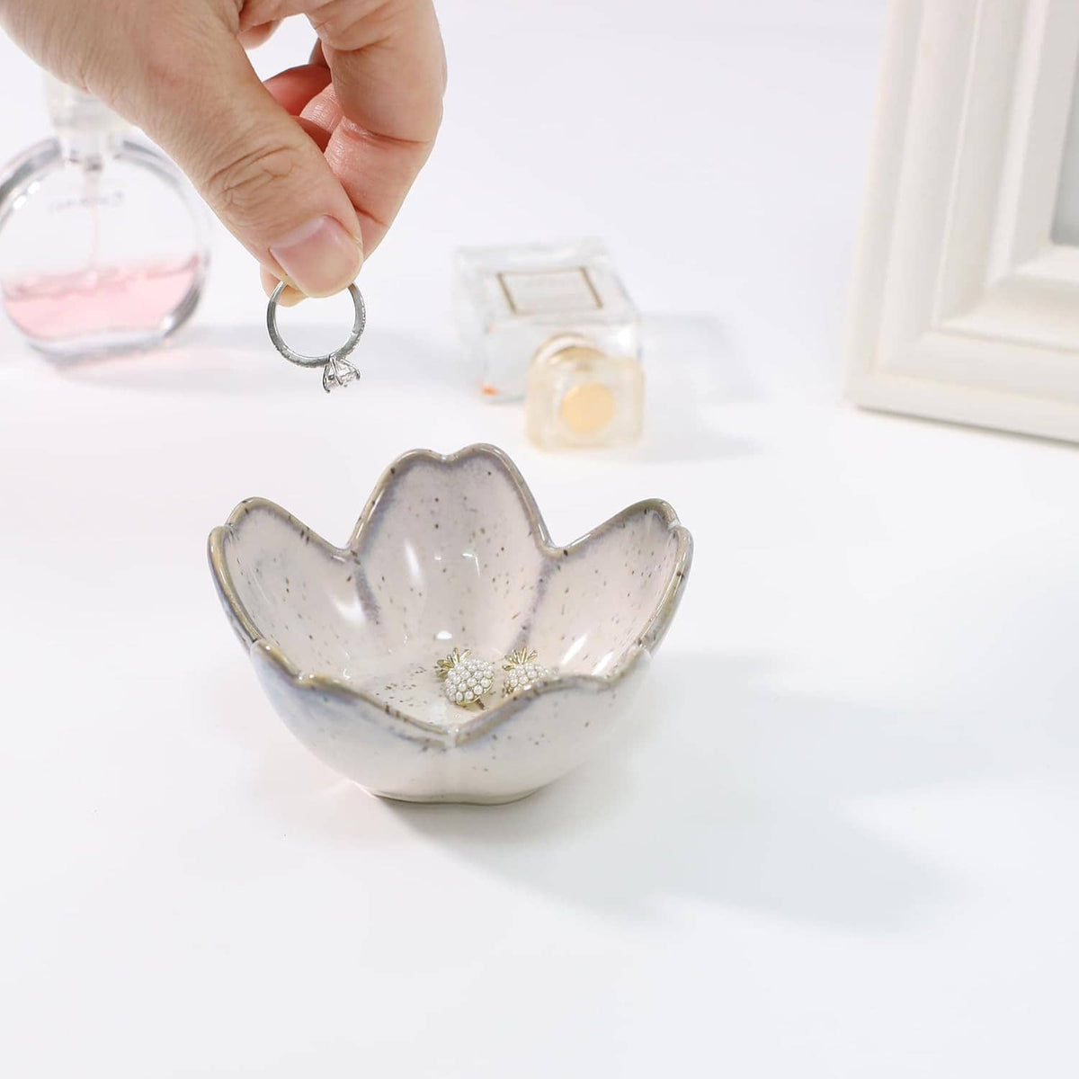 Ceramic flower-shaped trinket tray holding rings; hand holding a key ring