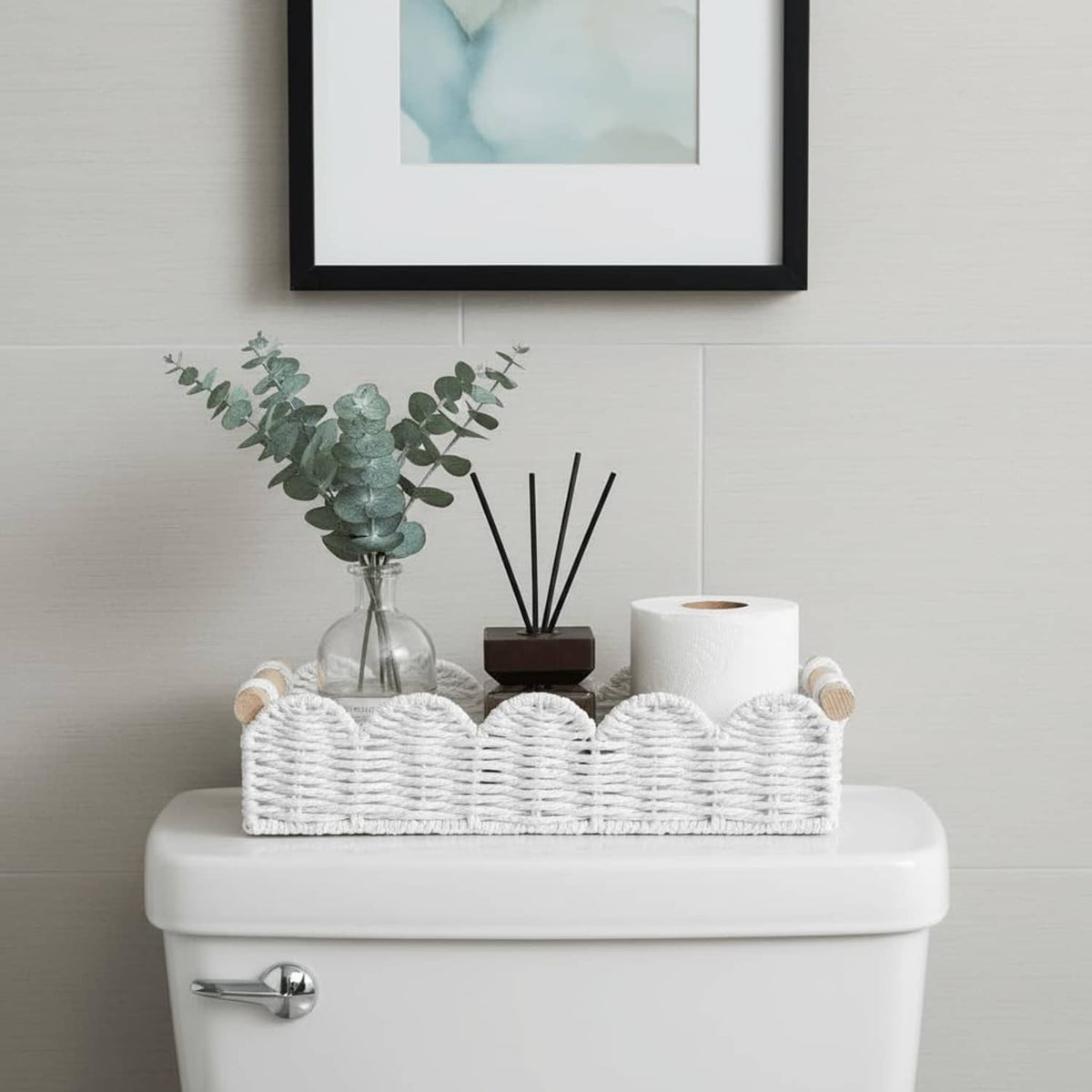 White woven storage basket with rope handles, holding toilet paper rolls and bathroom items