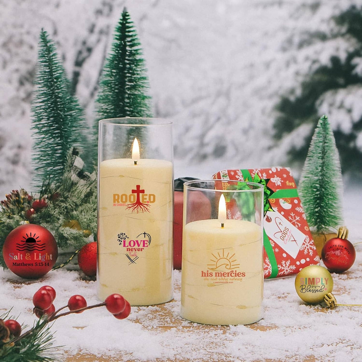 Christmas decor featuring faith-word candles and red ornaments on snowy tabletop