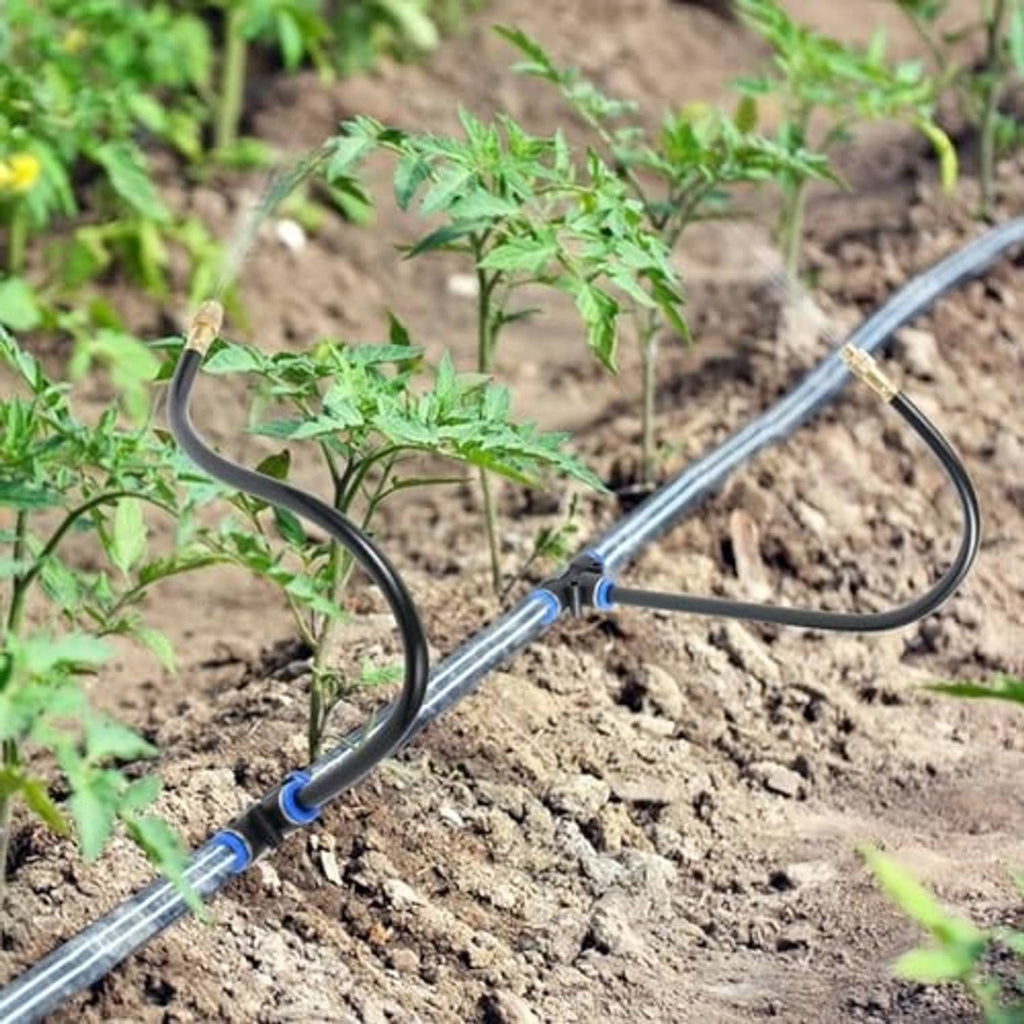 Misting nozzle tee with black hoses and blue connectors placed along soil for plants