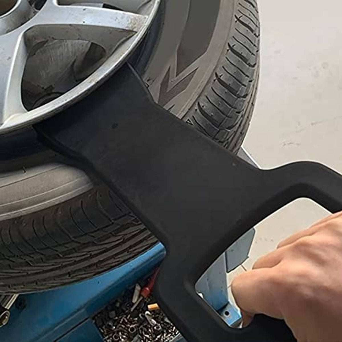 Black bead clamp tool positioned on wheel rim during tire change