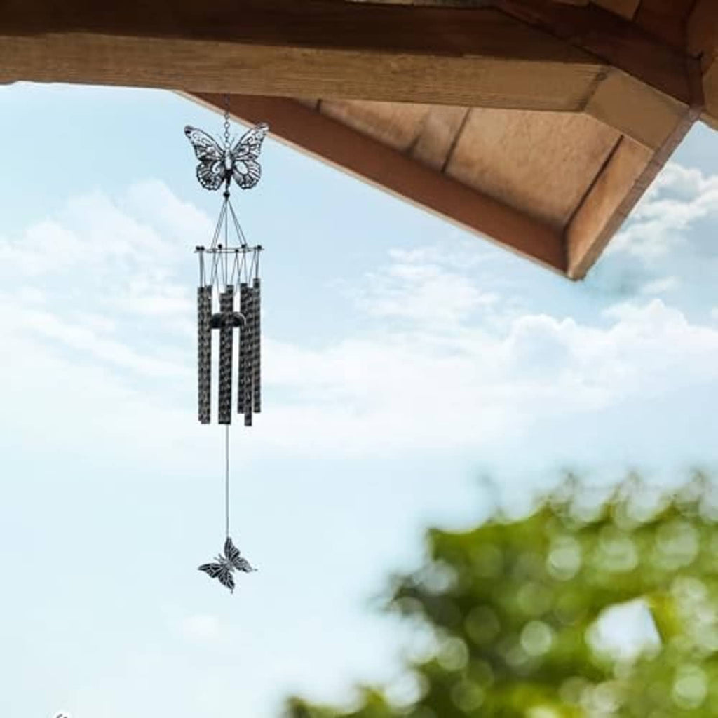 Black and white butterfly wind chime hanging under roof eaves with butterfly accents