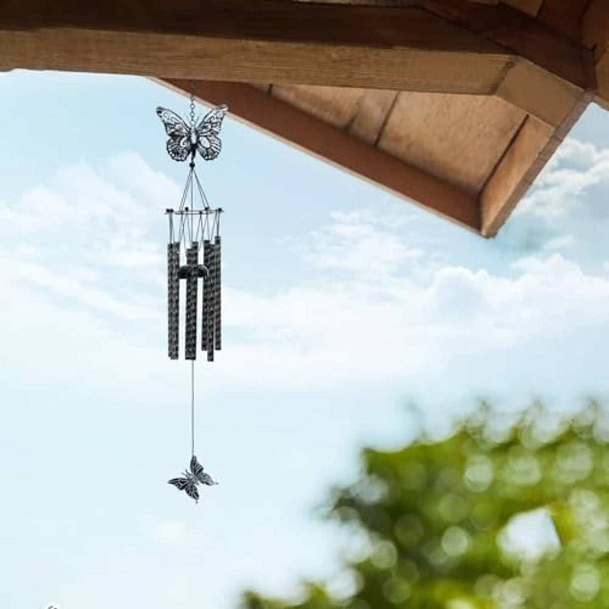 Black and white butterfly wind chime hanging under roof eaves with butterfly accents