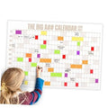 Dry-erase wall calendar with colorful blocks and labels, person writing with a marker