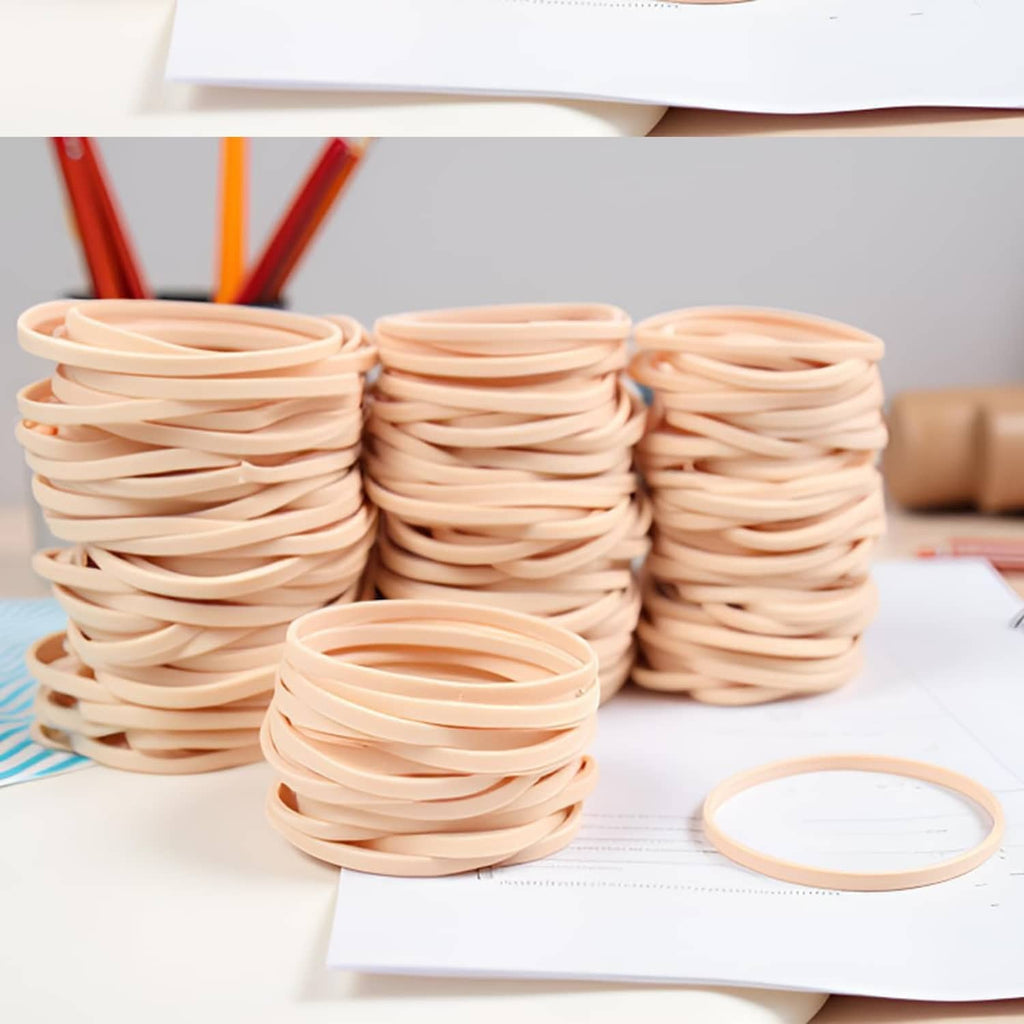 Beige elastic rubber bands in multiple stacks with one loose ring nearby
