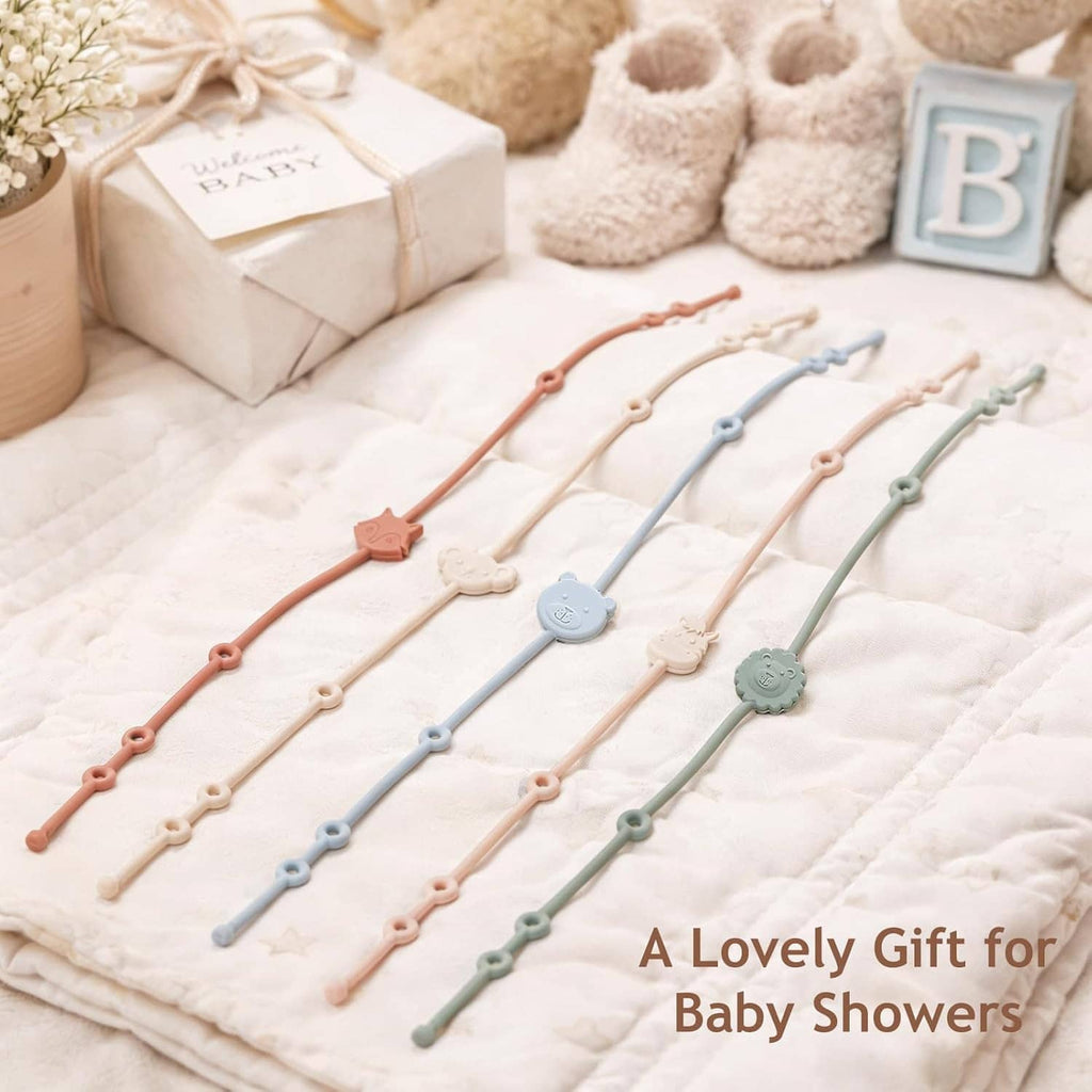Six silicone baby toy straps laid out on a blanket with pastel animal charms