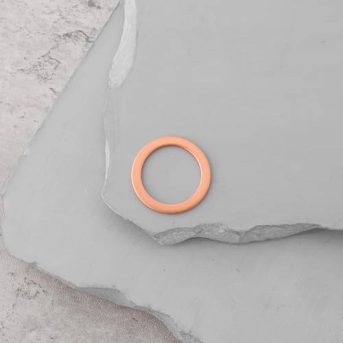 Small brown gasket washer ring on gray surface, round seal