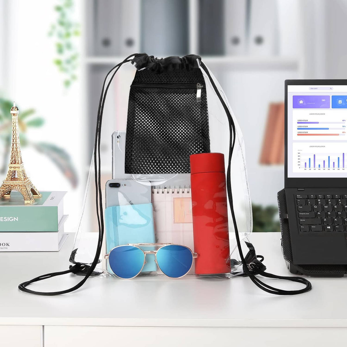 Black clear drawstring bag with front mesh pocket, filled with phone, sunglasses, toiletries