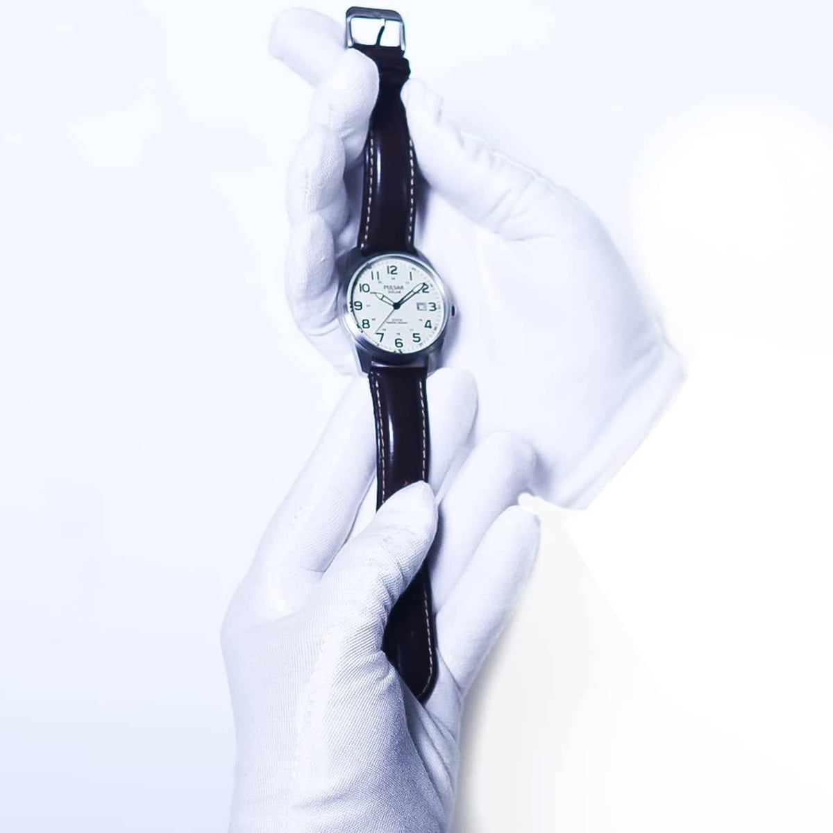 White cotton gloves holding a wristwatch, long cuffs