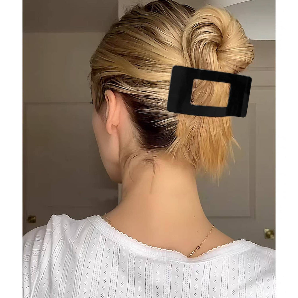Bright black flat rectangular hair clip holding a side bun in blonde hair
