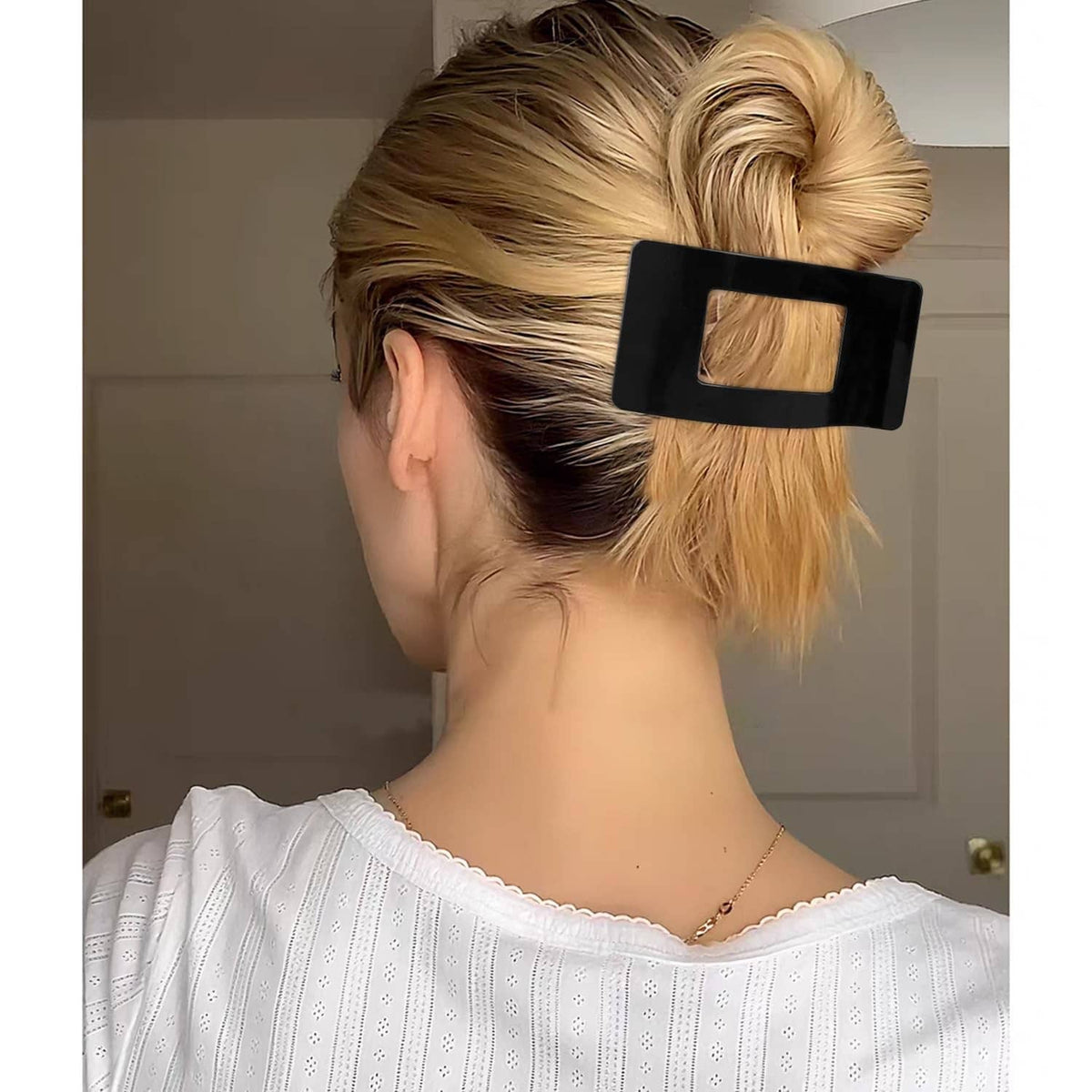 Bright black flat rectangular hair clip holding a side bun in blonde hair