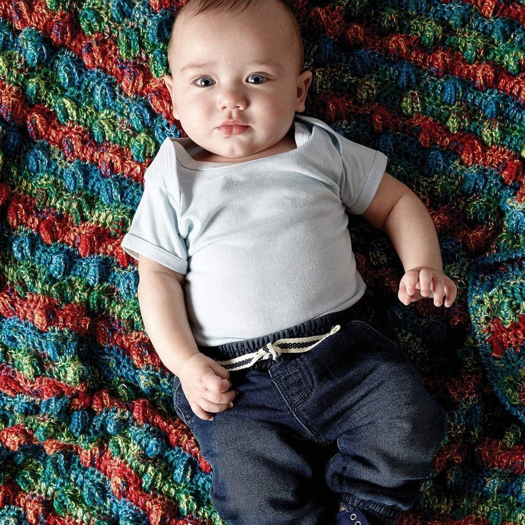 Baby resting on a multicolor chunky knit blanket made with soft baby yarn
